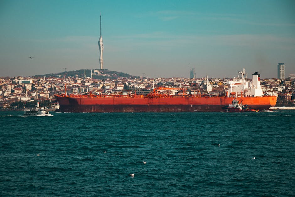 A large oil tanker navigates the Bosphorus Strait with Istanbul's skyline and Camlica Tower in the background.