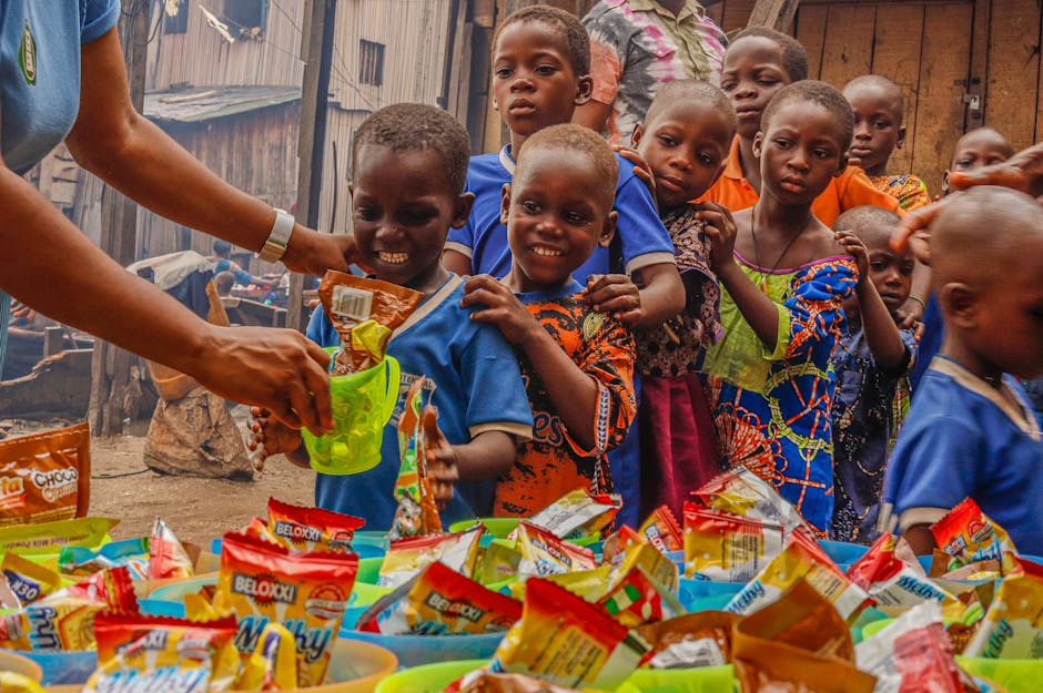 Joyful children receiving food supplies from a volunteer in an outdoor setting.