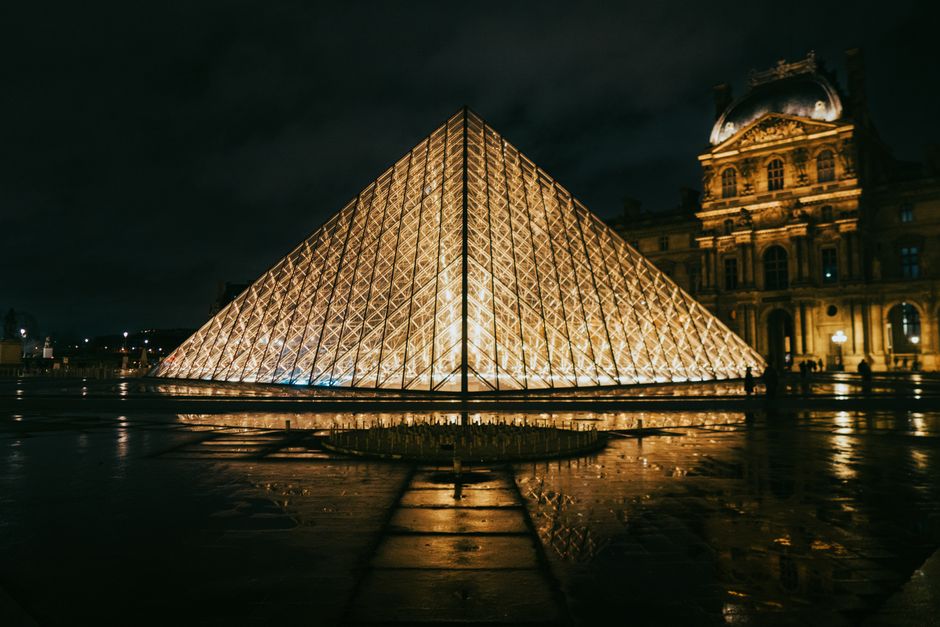 View of the Louvre Pyramid glowing at night, showcasing modern architecture in Paris, France.