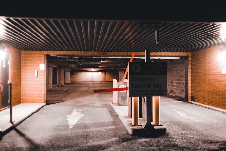 Entrance to an illuminated underground parking lot in an urban setting, highlighting modern architecture and security.